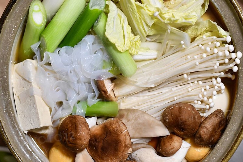 Top view of Japanese nabe or nabemono soup dish with unkooked Chinese cabbage, tofu, enoki and shitake mushrooms and Shirataki noodles in