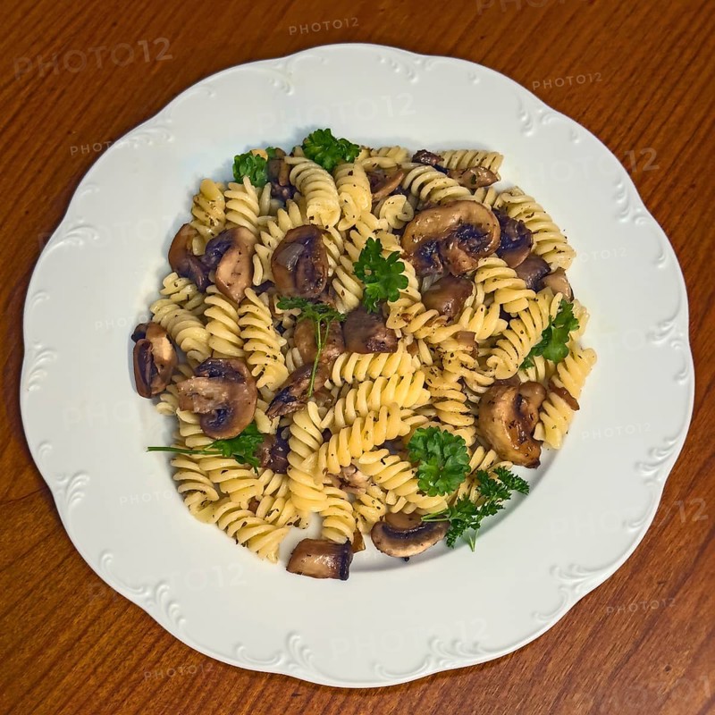 Simple Italian dish pasta fusilli with mushrooms garnished with parsley, vegan cuisine, international