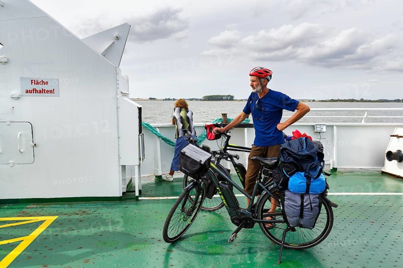 Cyclist with helmet, bicycle tour, e-bike with luggage bags on a ferry, Baltic Sea, Germany