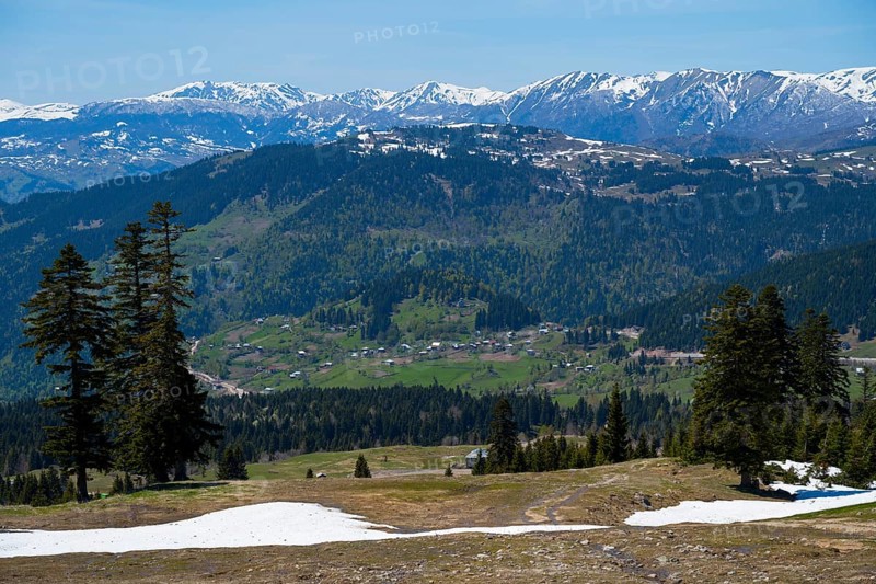 Panorama with snow-capped mountains, green valley and isolated houses under blue sky, view from Goderdzi Pass, Ajara region, Adjara, autonomous republic, Georgia