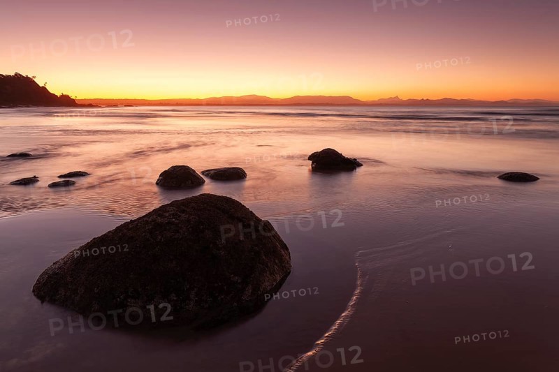 Washed stones and rocks on a beach at sunset in Byron Bay, Wategos Beach, New South Wales, Australia