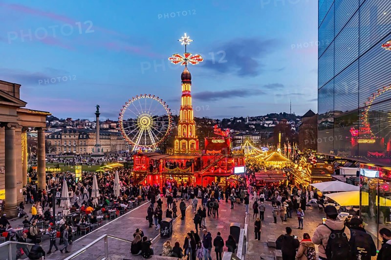 Evening atmosphere at Stuttgart's Christmas market in the Schlossplatz area. With around 3.5 million visitors, it is one of the largest and most beautiful in all of Germany. Christmas pyramid and Ferris wheel in front of the New Castle. Stuttgart, Baden-WÃ¼rttemberg, Germany