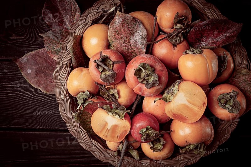 Fresh persimmon in a basket, with leaves, top view, no people