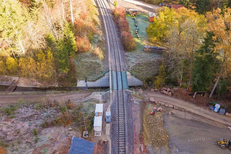 Autumn aerial view of railroad crossing and tracks surrounded by trees, Hermann Hesse Railway bat tunnel construction site, Calw, Black Forest, Germany