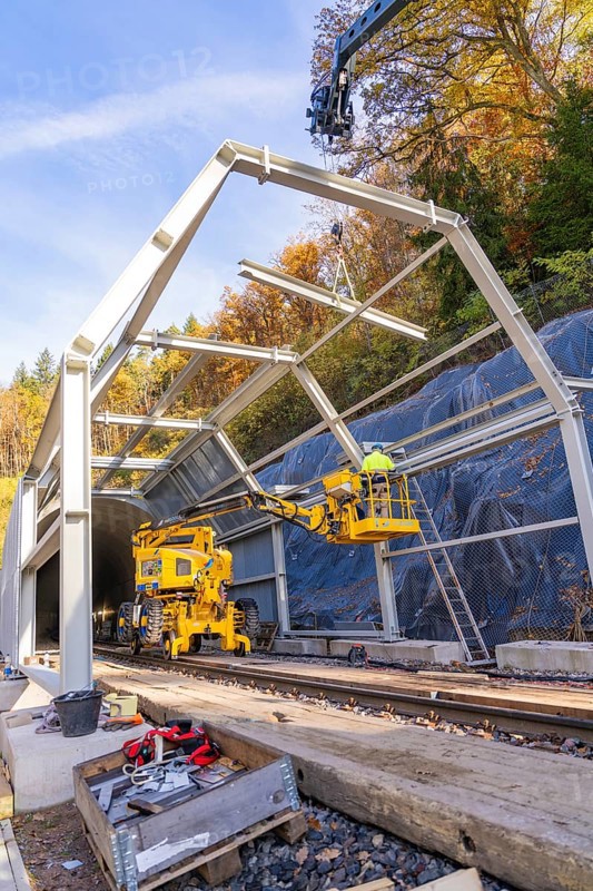 Construction work at a tunnel entrance in autumn with yellow construction equipment and visible nature in the background, Hermann Hesse Railway bat tunnel construction site, Calw, Black Forest, Germany