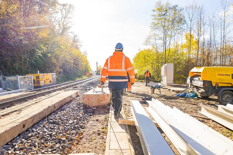 Construction workers in glowing vests work on a railway construction site under clear skies, Hermann Hesse Railway Bat Tunnel construction site, Calw, Black Forest, Germany