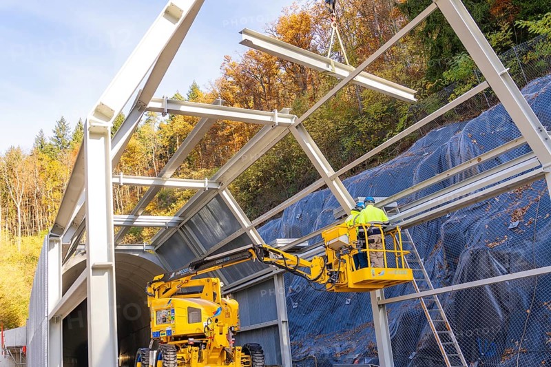 Workers on a lift building tunnel surrounded by colorful autumn trees, Hermann Hesse Railway bat tunnel construction site, Calw, Black Forest, Germany