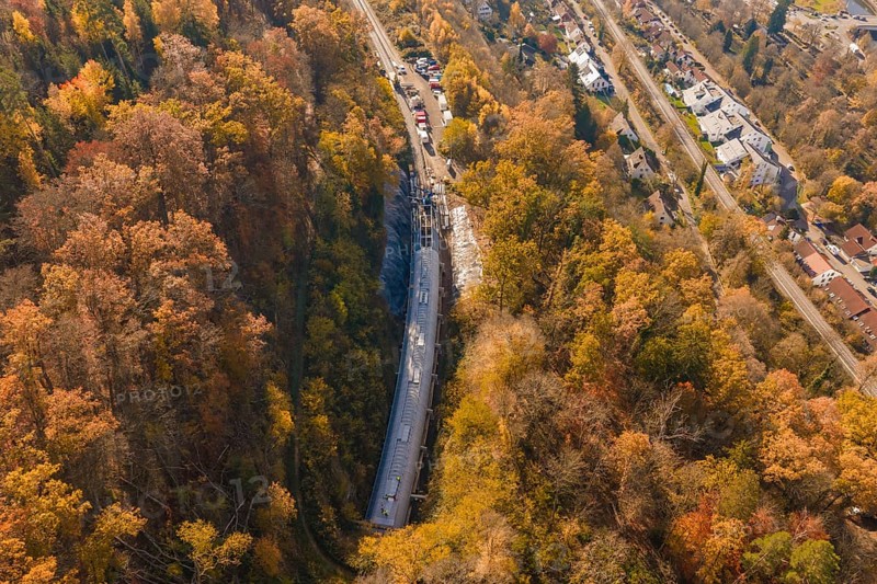 Aerial view of a construction site in colorful autumn forest with adjacent roads and houses, Hermann Hesse Railway bat tunnel construction site, Calw, Black Forest, Germany
