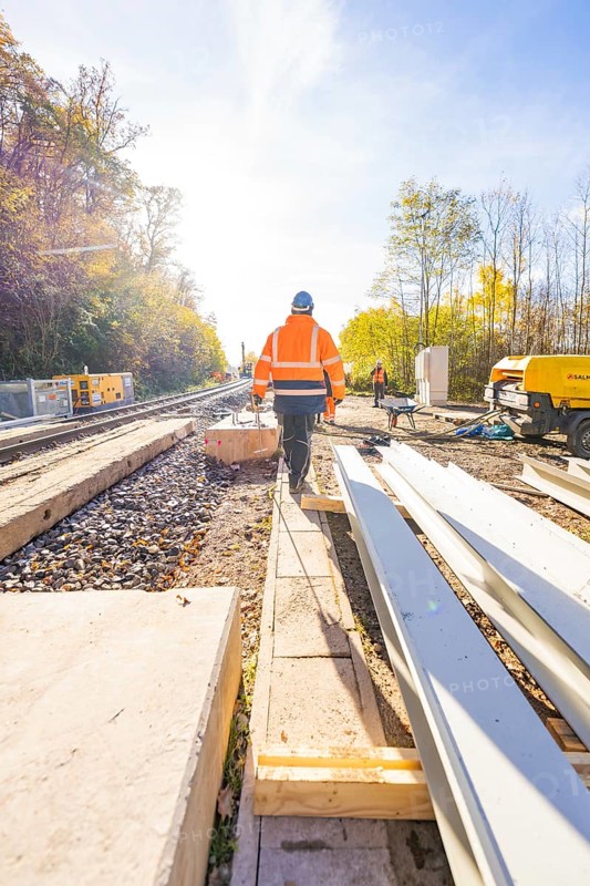 People wearing protective clothing on a construction site along the tracks in sunny weather, Hermann Hesse Railway bat tunnel construction site, Calw, Black Forest, Germany