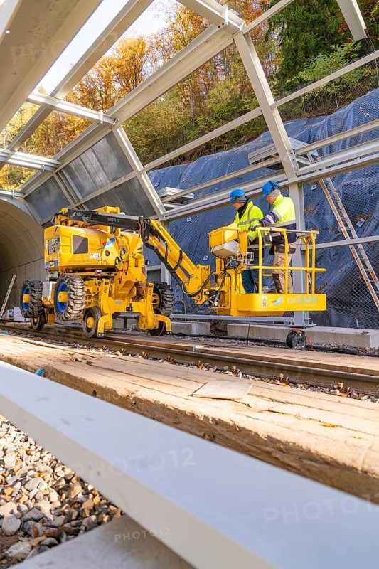 Two workers operate yellow machines in a partially built metal structure, Hermann Hesse Railway Bat Tunnel construction site, Calw, Black Forest, Germany