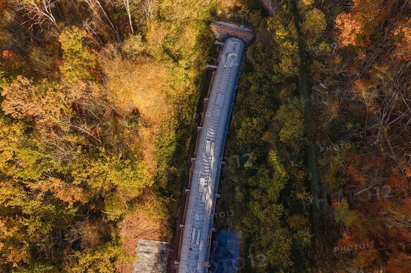 Autumn forest frames a tunnel construction project, shown in a colorful aerial view, Hermann Hesse Railway Bat Tunnel construction site, Calw, Black Forest, Germany