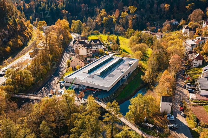 Building with solar panels in the middle of a picturesque autumn landscape with river and forest, PV at Walther Lindner Sporthalle Calw, Black Forest, Germany