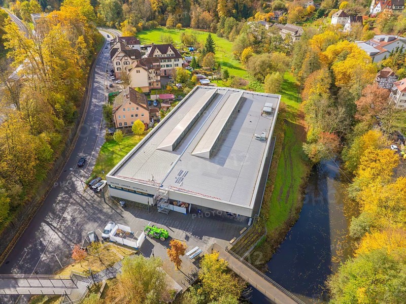Panorama of a modern building with solar panels, embedded in an autumnal village and river environment, PV at Walther Lindner Sporthalle Calw, Black Forest, Germany