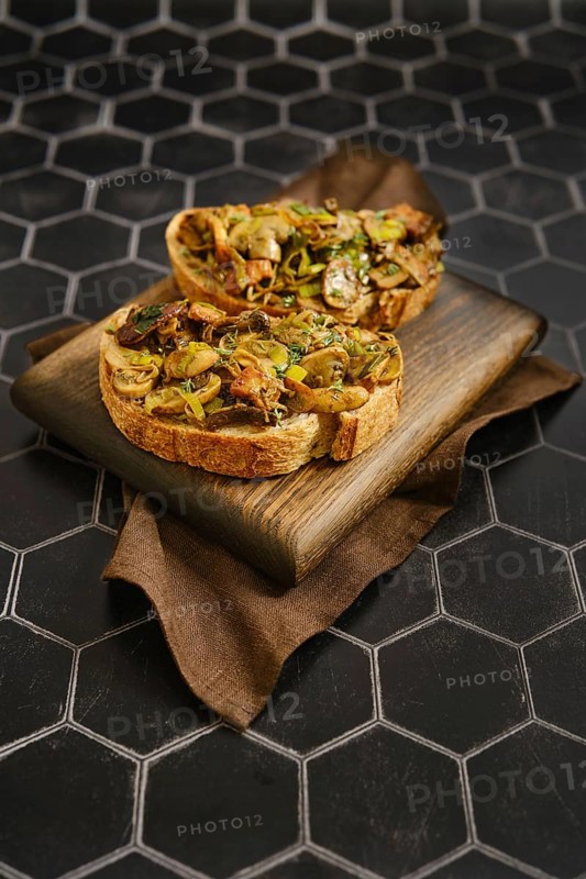 A tasty mushroom sandwiches feature fried honey mushrooms, enoki mushrooms, champignon, and leek. The dish rests on a wooden board, showcasing its rich, earthy flavors and textures, perfect for lunch