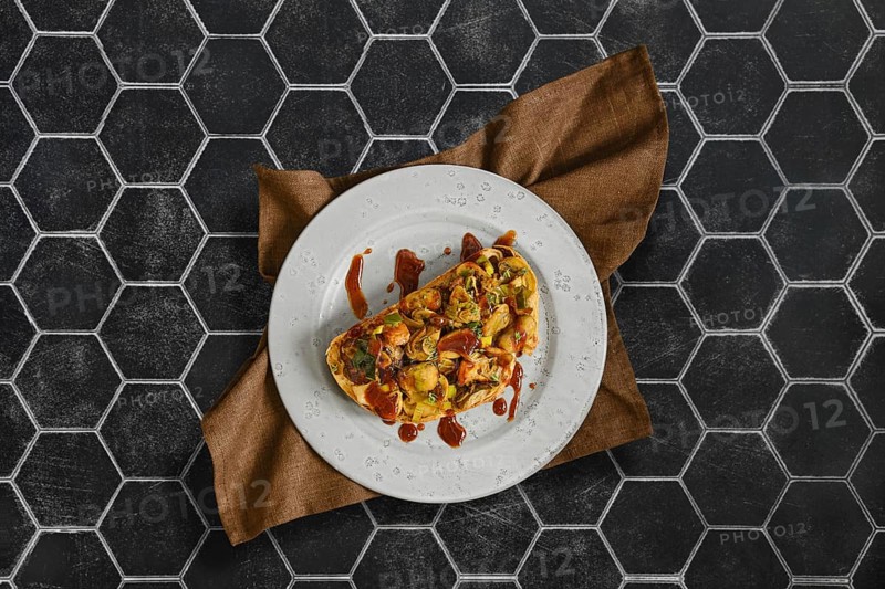 This tasty sandwich combines honey mushroom, enoki mushroom, champignon, and leek on fresh bread. It is carefully arranged on a white plate and set against a stylish hexagonal background