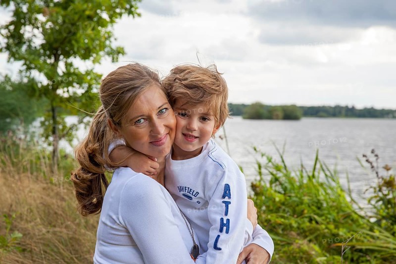 Pregnant woman with little boy at lake, mom and child hugging