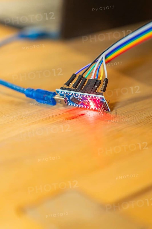 Red glowing circuit board connected to USB cable on wooden table, Jugend Forschungszentrum Nagold, Calw district, Germany