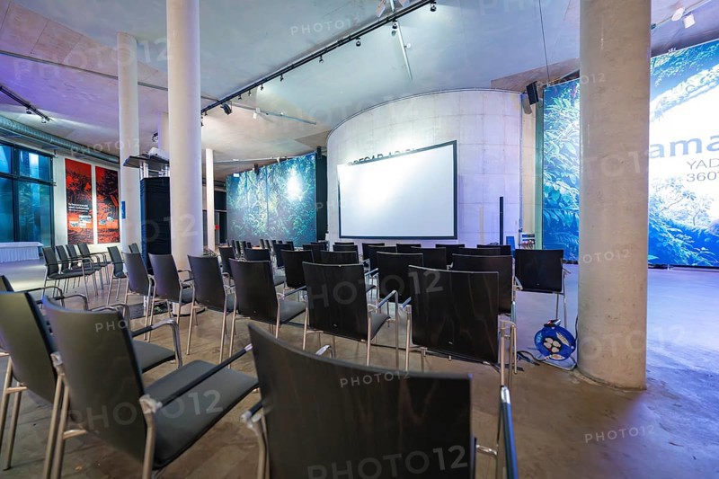 Empty conference room with chairs and a large projection screen under a high roof, Amazonia exhibition, Gasometer, Pforzheim, Germany