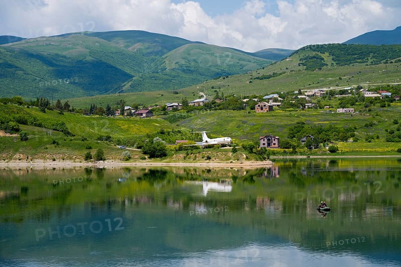 Lakeside village with mountains in the background, calm water with reflection, Tu-134A aircraft as an exhibit at Hrazdan Reservoir, Kotayk Province, Armenia
