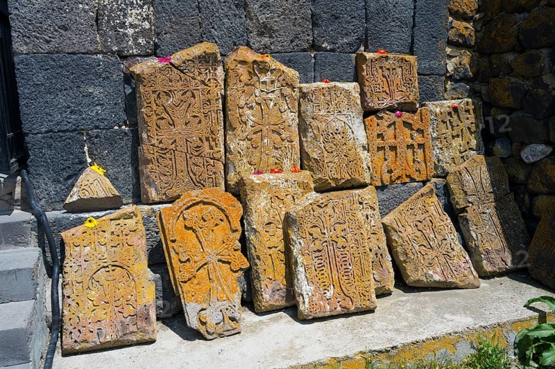 Historical, engraved stones with flowers on concrete in front of a wall, cross stones at Sevanavank monastery, Sevan monastery, Gegharkunik province, Armenia