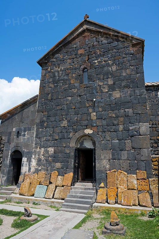 Old stone building with open door and roof under blue sky, cross stones at Sevanavank monastery, Sevan monastery, Gegharkunik province, Armenia