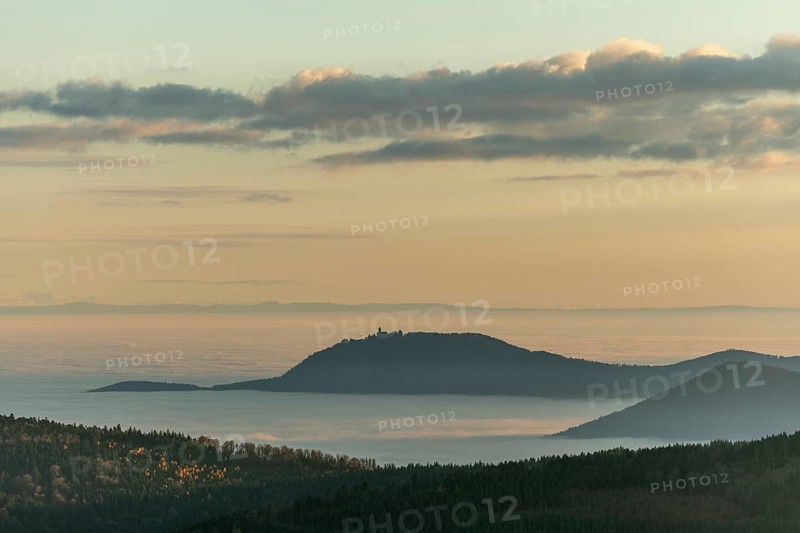 The landscape of hills and mountains is illuminated by a gentle sunset. Sea of fog in distance inspire peaceful and serene atmosphere. Bas Rhin, Alsace, France