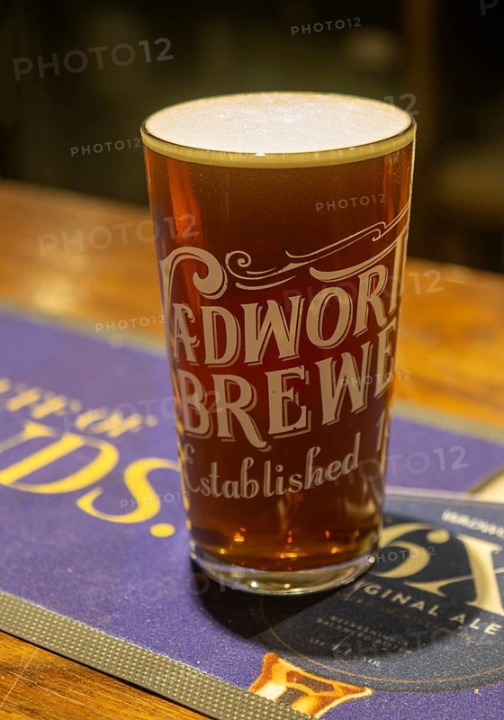 Full pint glass of Wadworth 6X real ale beer on pub bar mat, Wiltshire, England, UK