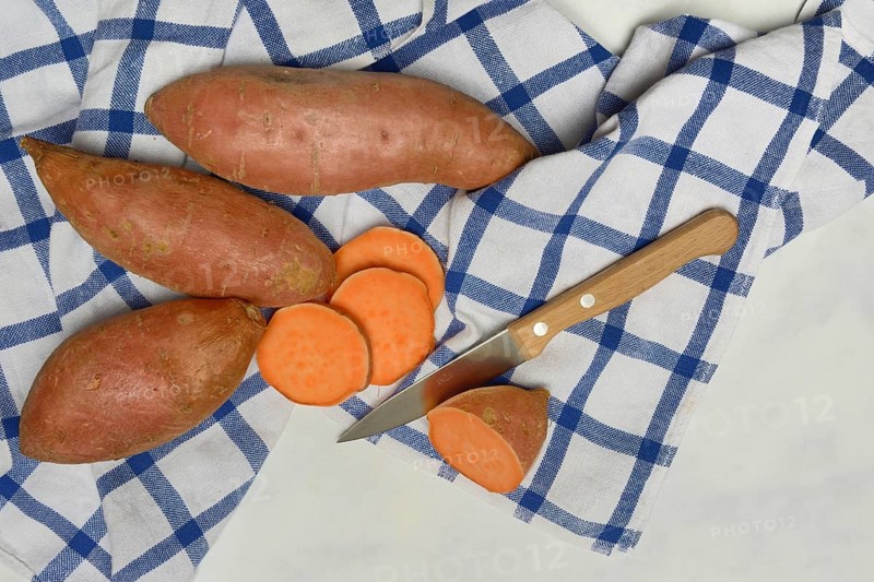 Sweet potatoes with kitchen knife on kitchen towel, Ipomoea batatas