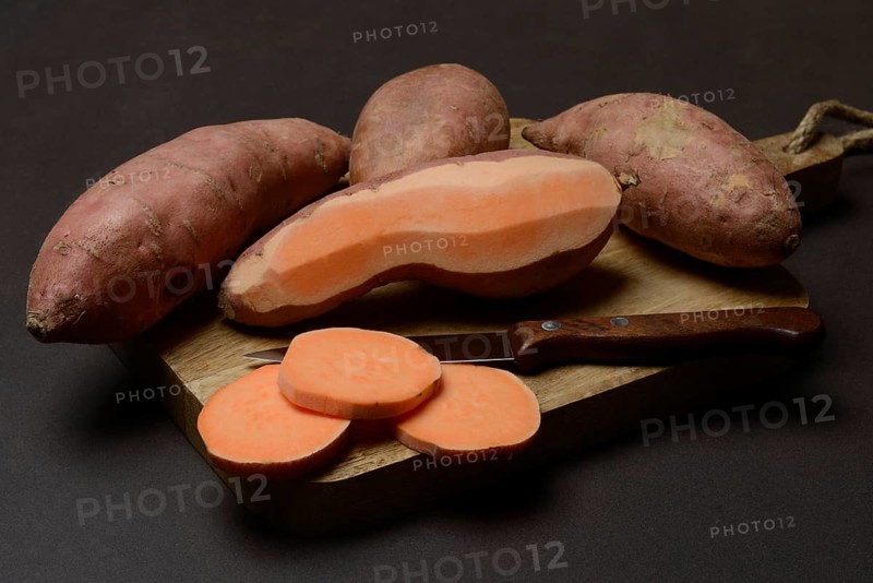 Sweet potatoes with kitchen knife on wooden board, Ipomoea batatas