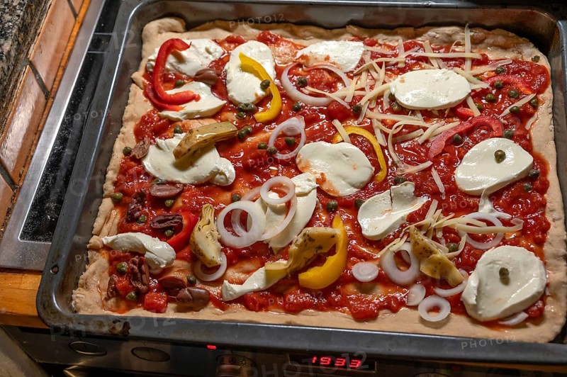Homemade pizza topped with gorgonzola and tomatoes, olives and peppers on a baking tray in front of baking, Othenstorf, Mecklenburg-Western Pomerania, Germany