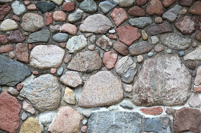 Rustic stone wall made of uneven natural stones in different colors