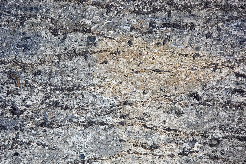 Natural stone surface with beige and grey hues and complex texture