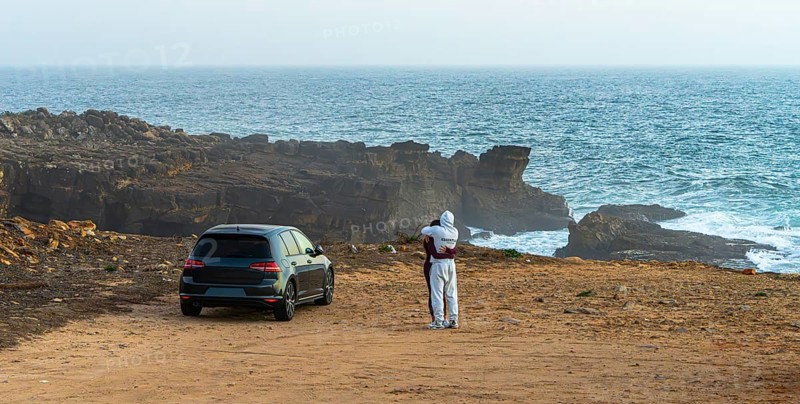 Young couple in love standing on the coast of Farol de Cabo Raso lighthouse, SÃ£o Bras de Sanxete fortress, Cascais, Portugal