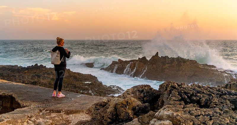 Young tourist standing on the coast of Farol de Cabo Raso lighthouse, SÃ£o Bras de Sanxete fortress, Cascais, Portugal