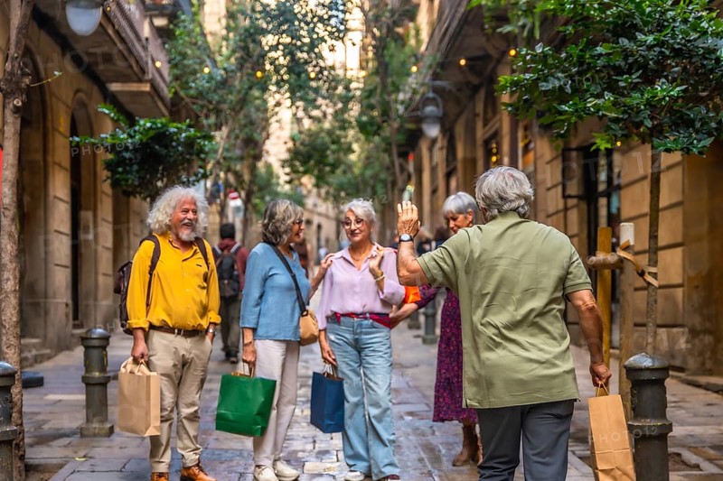 Group of diverse senior friends meeting and greeting on a charming narrow urban street, enjoying a shopping day and social interaction during their active retirement