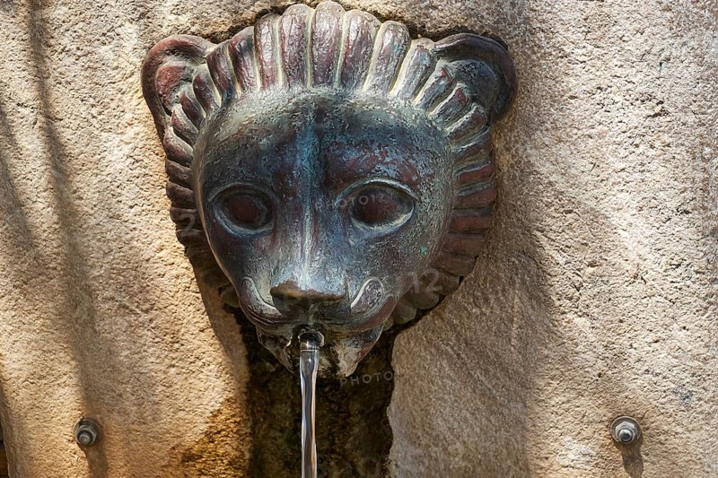 A bronze lion head sculpture that serves as a fountain and steers water in an ancient setting, Ancient Stadium, Nemea, Peloponnese, Greece