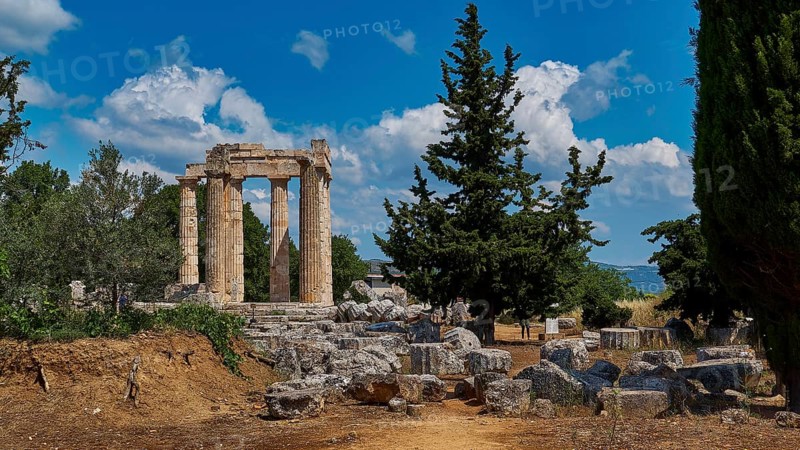 Ruins of an ancient temple against a blue sky with trees and scattered stones, Ancient Zeus Sanctuary, Nemea, Peloponnese, Greece