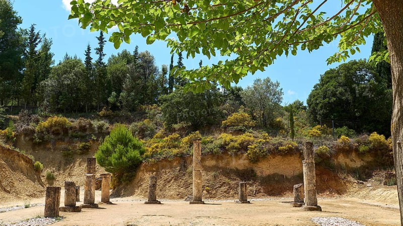 Ancient ruins with multiple pillars nestled in a lush green landscape under cloudy sky, Ancient Stadium, Nemea, Peloponnese, Greece