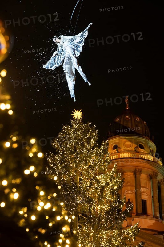 An artist hovers on a crane over the Christmas tree in front of the German Cathedral at the Christmas market WeihnachtsZauber Gendarmenmarkt on the Gendarmenmarkt, Berlin, 24.11.2025