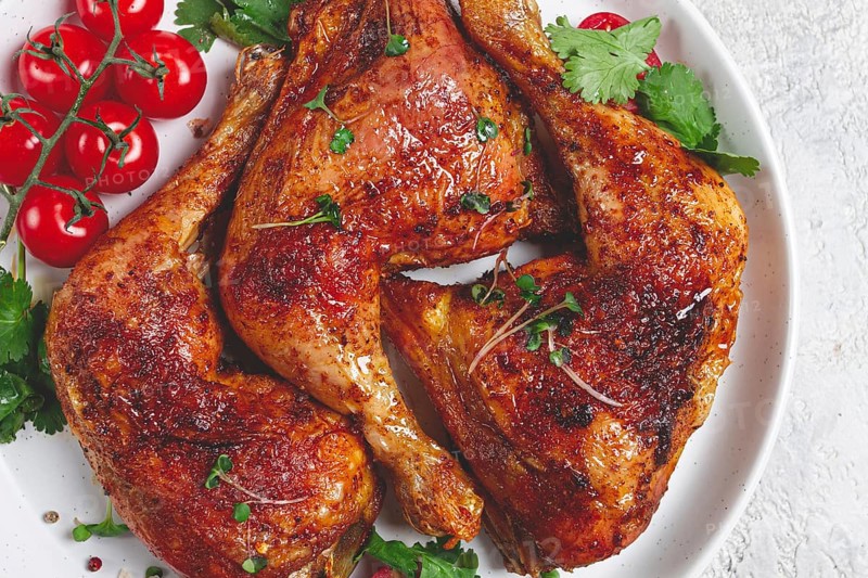 Grilled fried chicken legs, served, with fresh cherry tomatoes, and herbs, on a white plate, homemade, no people