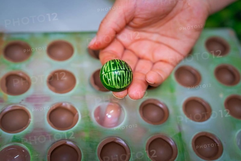 Hand holding green chocolate candy with Merry Christmas inscription out of a mold, Christmas baking, Haselstaller Hof, Wildberg, Calw district, Germany