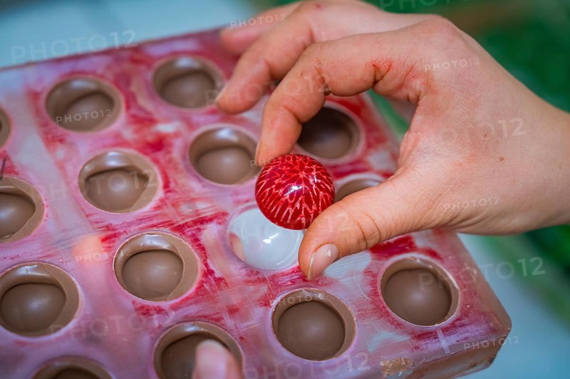 Hand picks red chocolate candy with white stripes from a chocolate mold, Christmas baking, Haselstaller Hof, Wildberg, Calw district, Germany