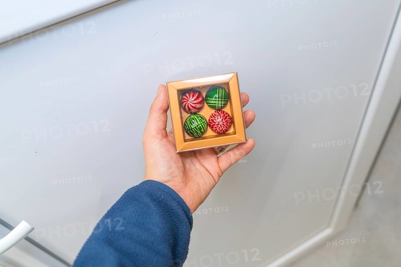 Person holding a chocolate box with patterned chocolates on a light background, Christmas baking, Haselstaller Hof, Wildberg, Calw district, Germany