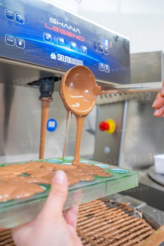 A ladle pours chocolate from a machine into green chocolate molds, Christmas baking, Haselstaller Hof, Wildberg, Calw district, Germany