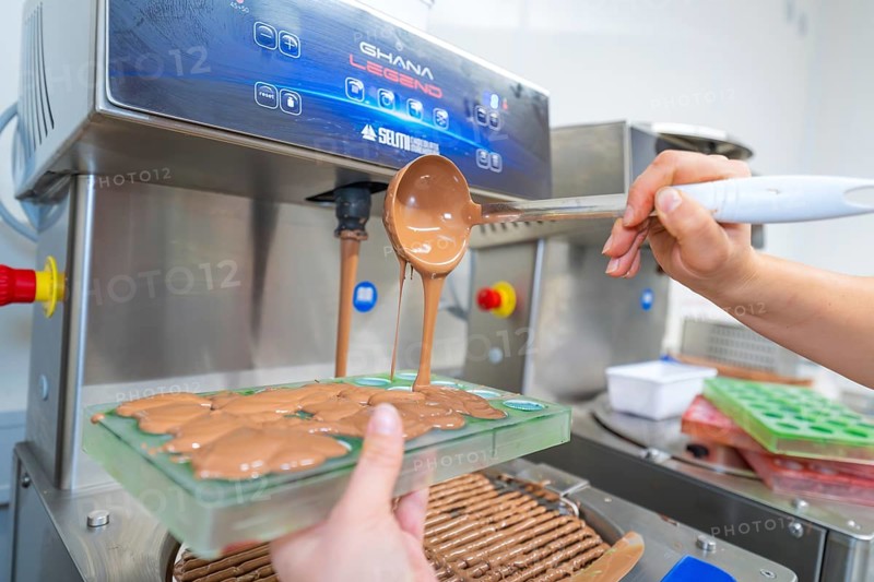 Chocolate filling is poured into molds from a tempering machine, Christmas baking, Haselstaller Hof, Wildberg, Calw district, Germany