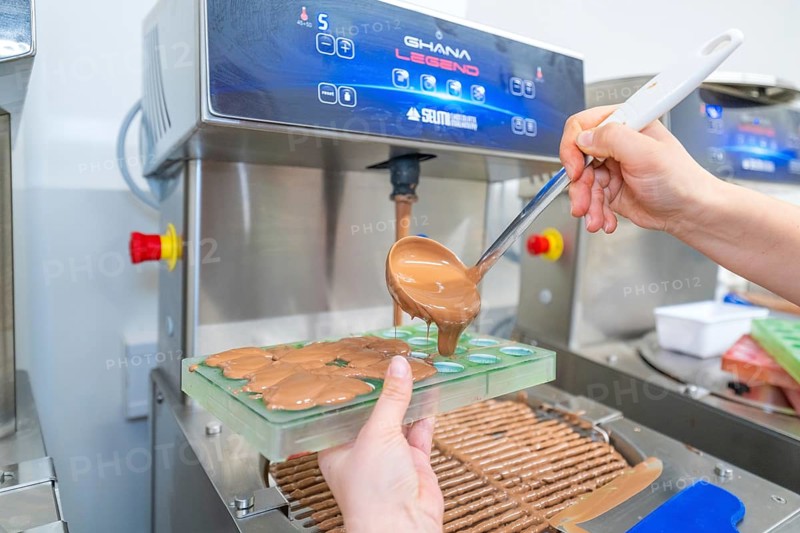 Chocolate is poured into molds from a machine with a ladle, Weihnachtsbacken, Haselstaller Hof, Wildberg, Calw district, Germany