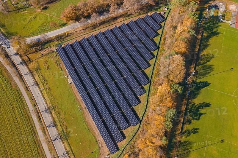 Aerial view of a solar plant surrounded by green fields and autumn trees, PV Freifaechenanlage construction, Weil der Stadt, Germany