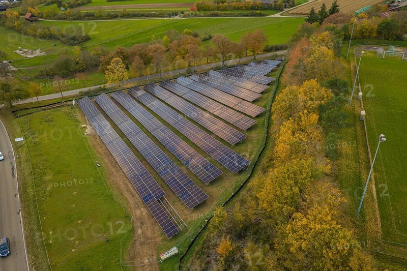 Solar system on a green area with autumn trees in the background, Bau PV Freifaechenanlage, Weil der Stadt, Germany