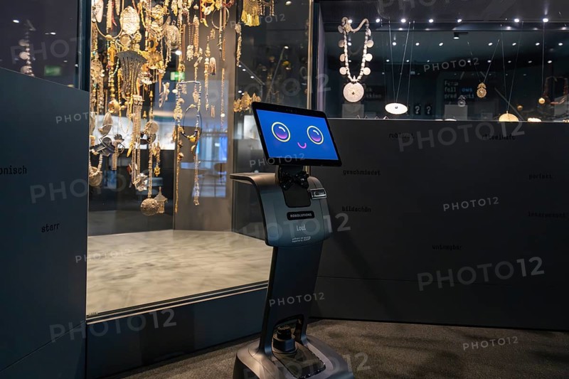 Smiling robot in front of display cabinet with jewelry in museum, robotic personality Roboloutions in jewelry museum, Pforzheim, Germany