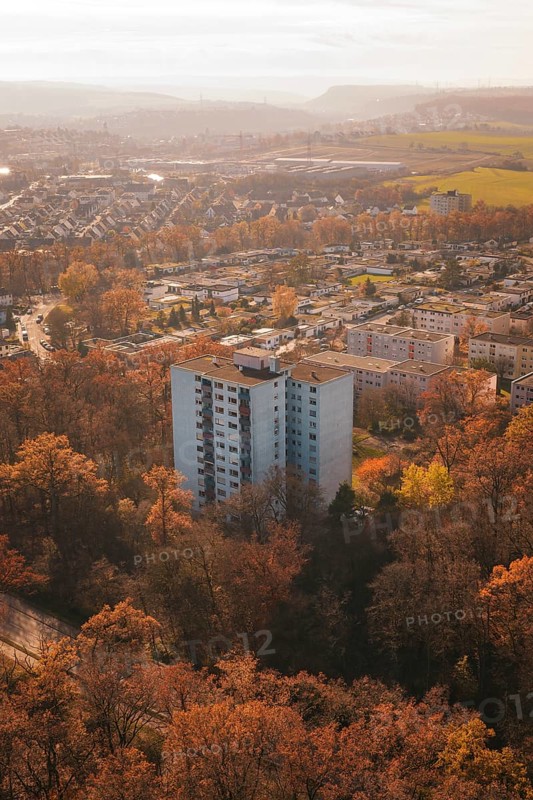 A high-rise residential building rises between autumn trees in an urban area, MÃ¼hlacker, Enzkreis, Germany
